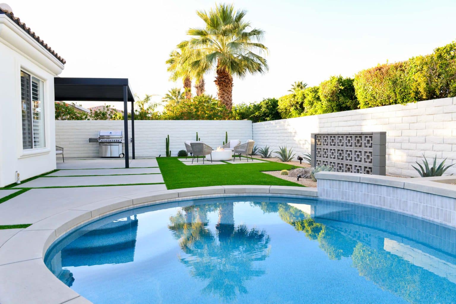 Backyard landscape transformation in Rancho Mirage including hardscape, fire feature, breeze block, masonry, low voltage lighting, artificial turf, irrigation and desert plants.