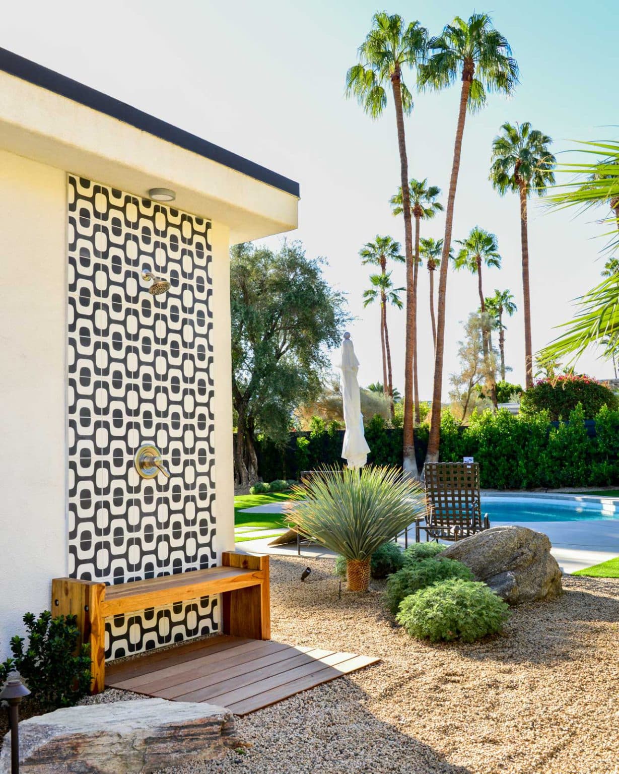 Complete residential landscape design and installation in Palm Springs, including hardscape, custom outdoor shower with tile, fire feature, low voltage lighting, boulders, artificial turf, irrigation and desert plants.