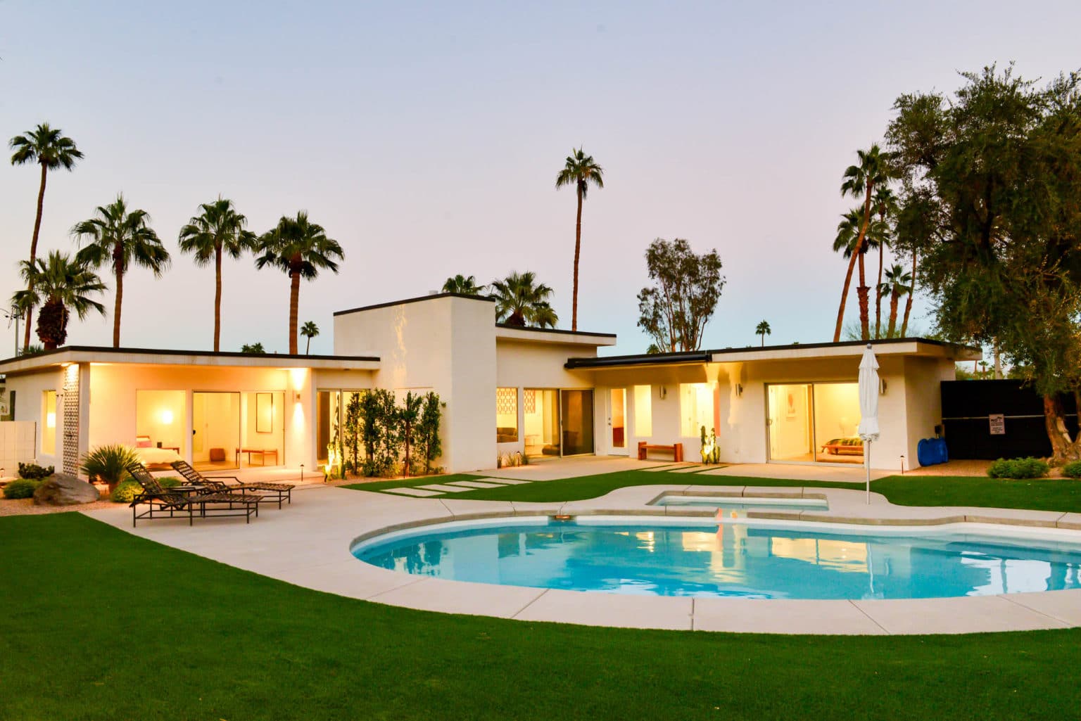 Complete residential landscape design and installation in Palm Springs, including hardscape, custom outdoor shower with tile, fire feature, low voltage lighting, boulders, artificial turf, irrigation and desert plants.