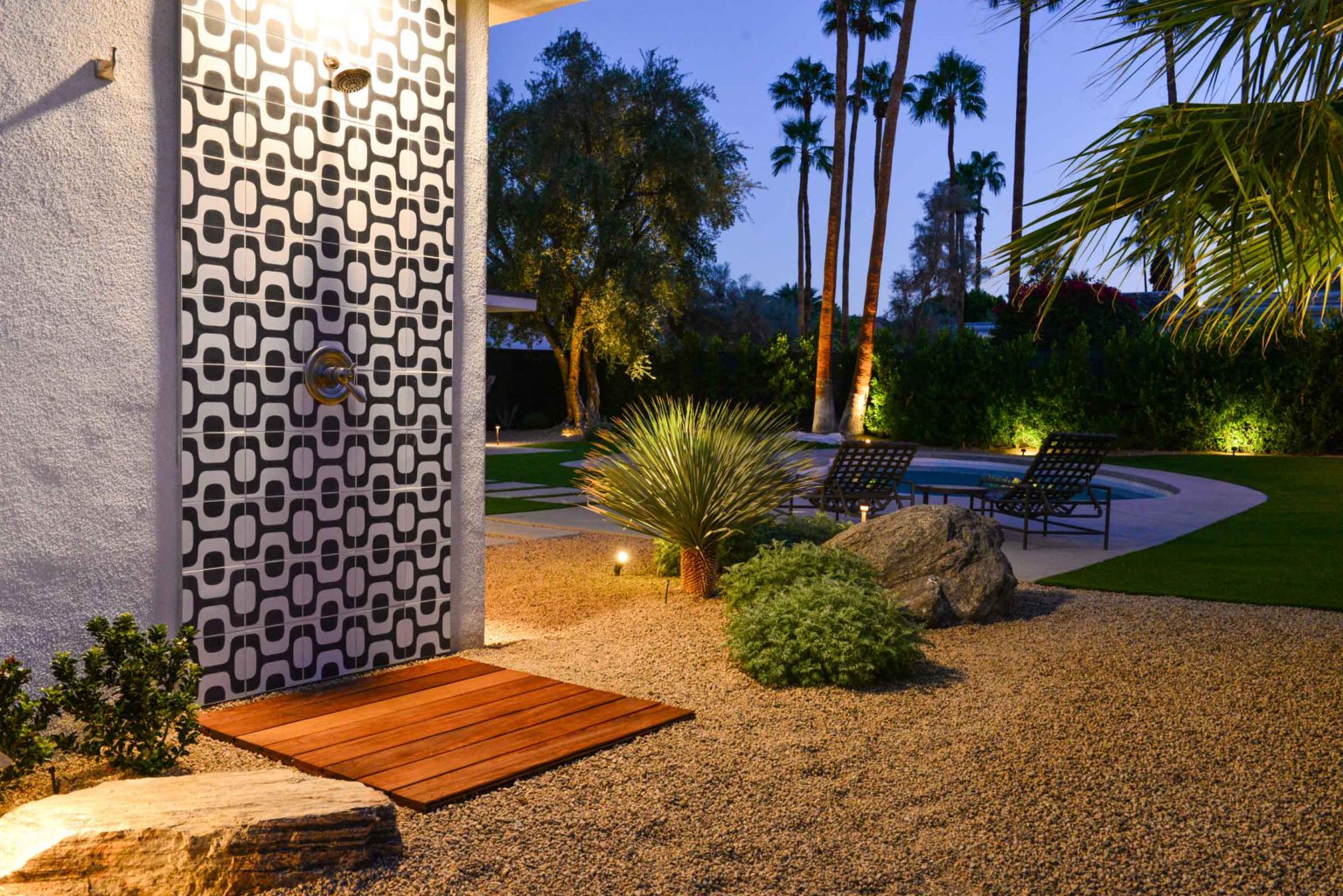 Complete residential landscape design and installation in Palm Springs, including hardscape, custom outdoor shower with tile, fire feature, low voltage lighting, boulders, artificial turf, irrigation and desert plants.