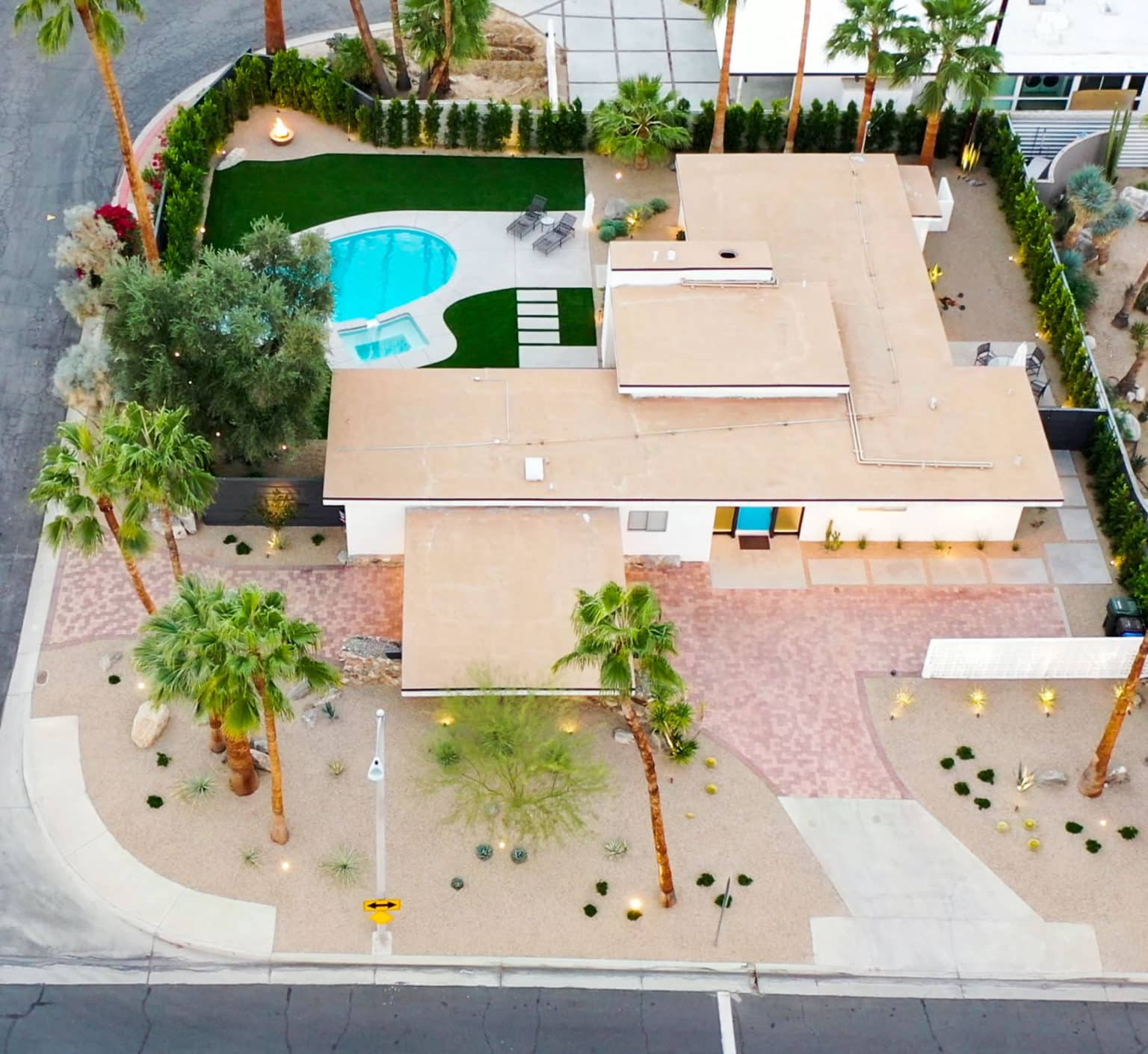 Complete residential landscape design and installation in Palm Springs, including hardscape, custom outdoor shower with tile, fire feature, low voltage lighting, boulders, artificial turf, irrigation and desert plants.