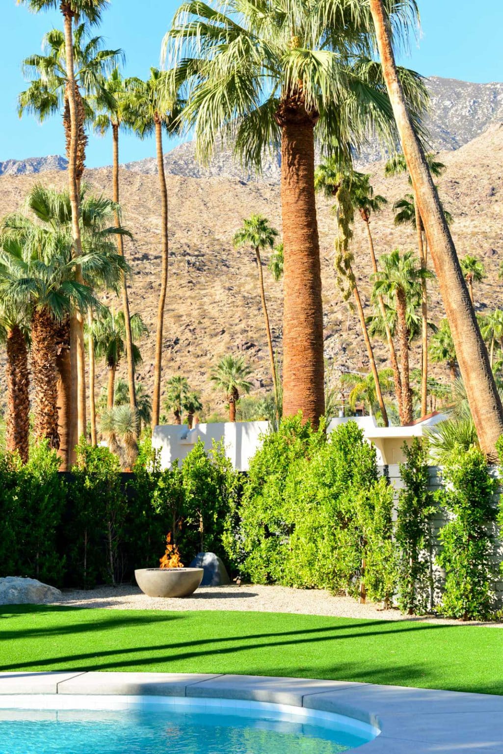 Complete residential landscape design and installation in Palm Springs, including hardscape, custom outdoor shower with tile, fire feature, low voltage lighting, boulders, artificial turf, irrigation and desert plants.