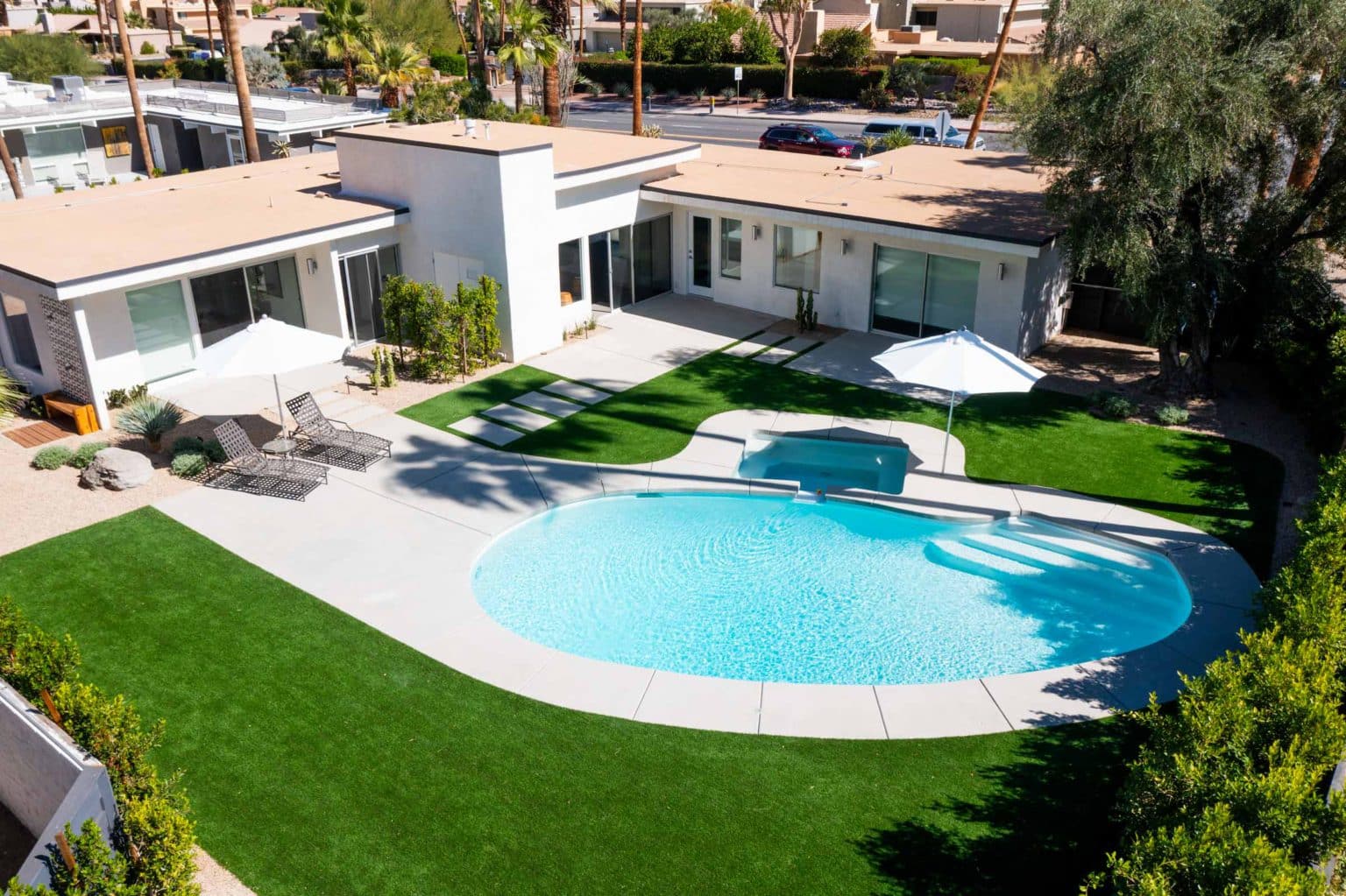 Complete residential landscape design and installation in Palm Springs, including hardscape, custom outdoor shower with tile, fire feature, low voltage lighting, boulders, artificial turf, irrigation and desert plants.