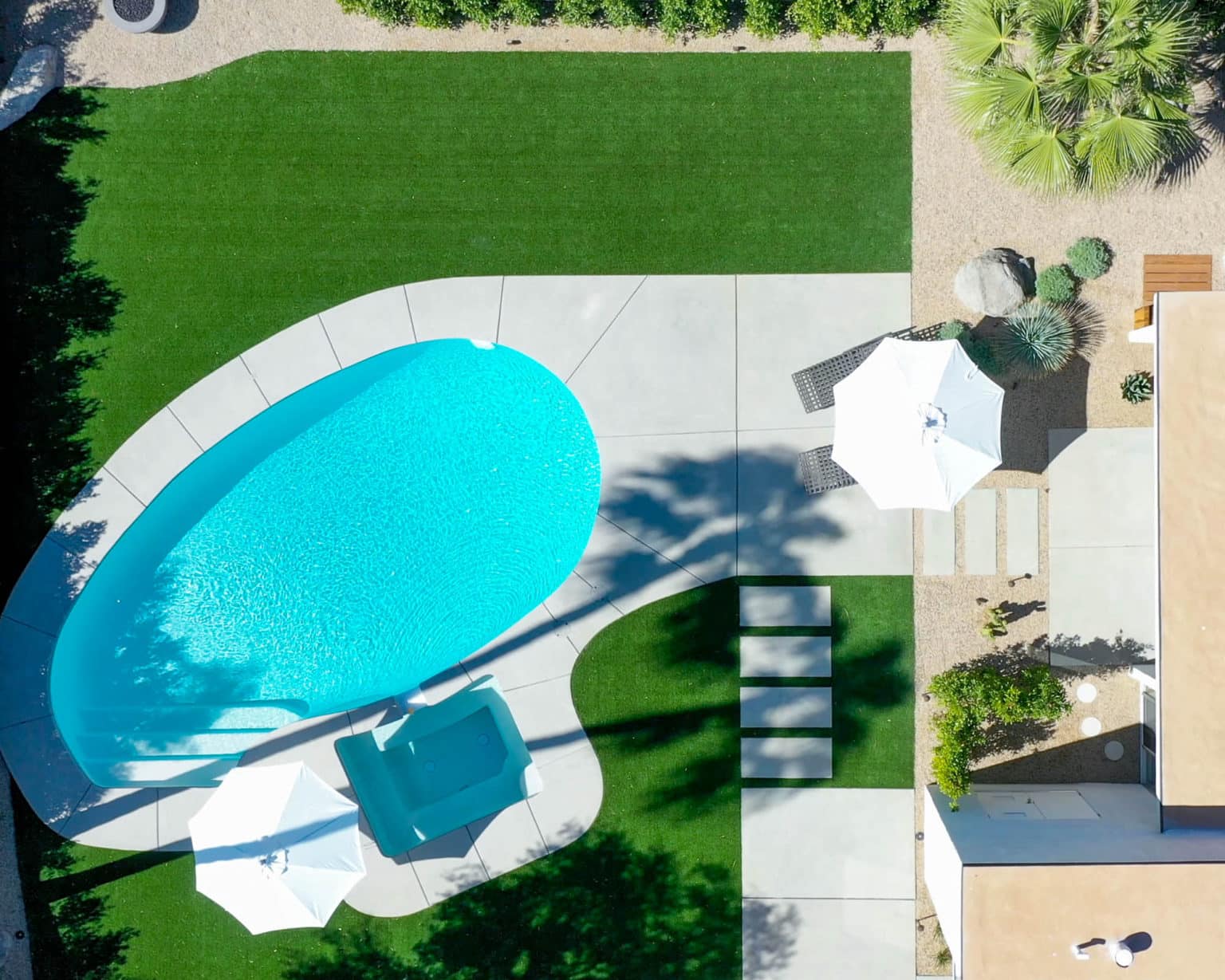 Complete residential landscape design and installation in Palm Springs, including hardscape, custom outdoor shower with tile, fire feature, low voltage lighting, boulders, artificial turf, irrigation and desert plants.