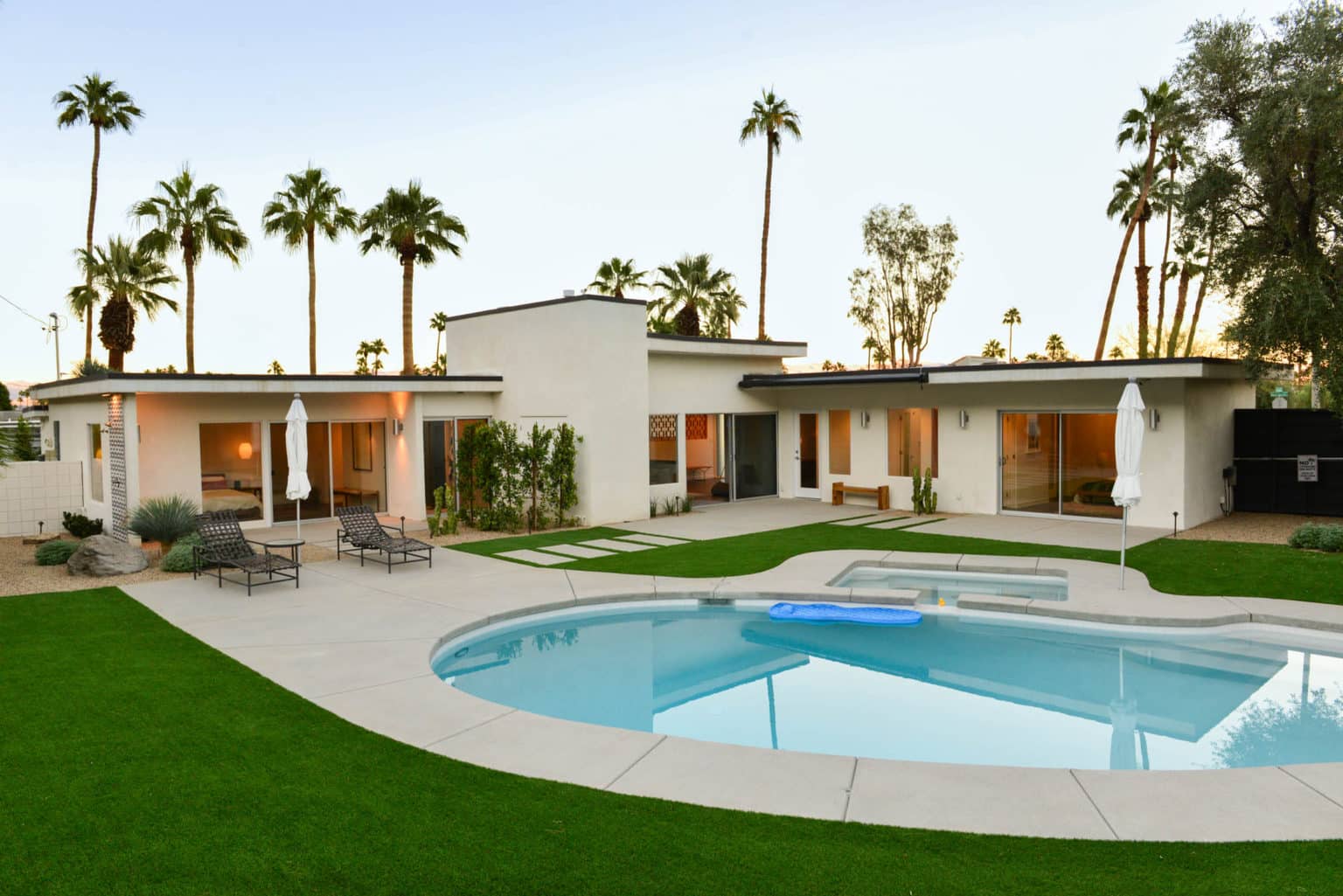Complete residential landscape design and installation in Palm Springs, including hardscape, custom outdoor shower with tile and wood flooring, fire feature, low voltage lighting, boulders, artificial turf, irrigation and desert plants.