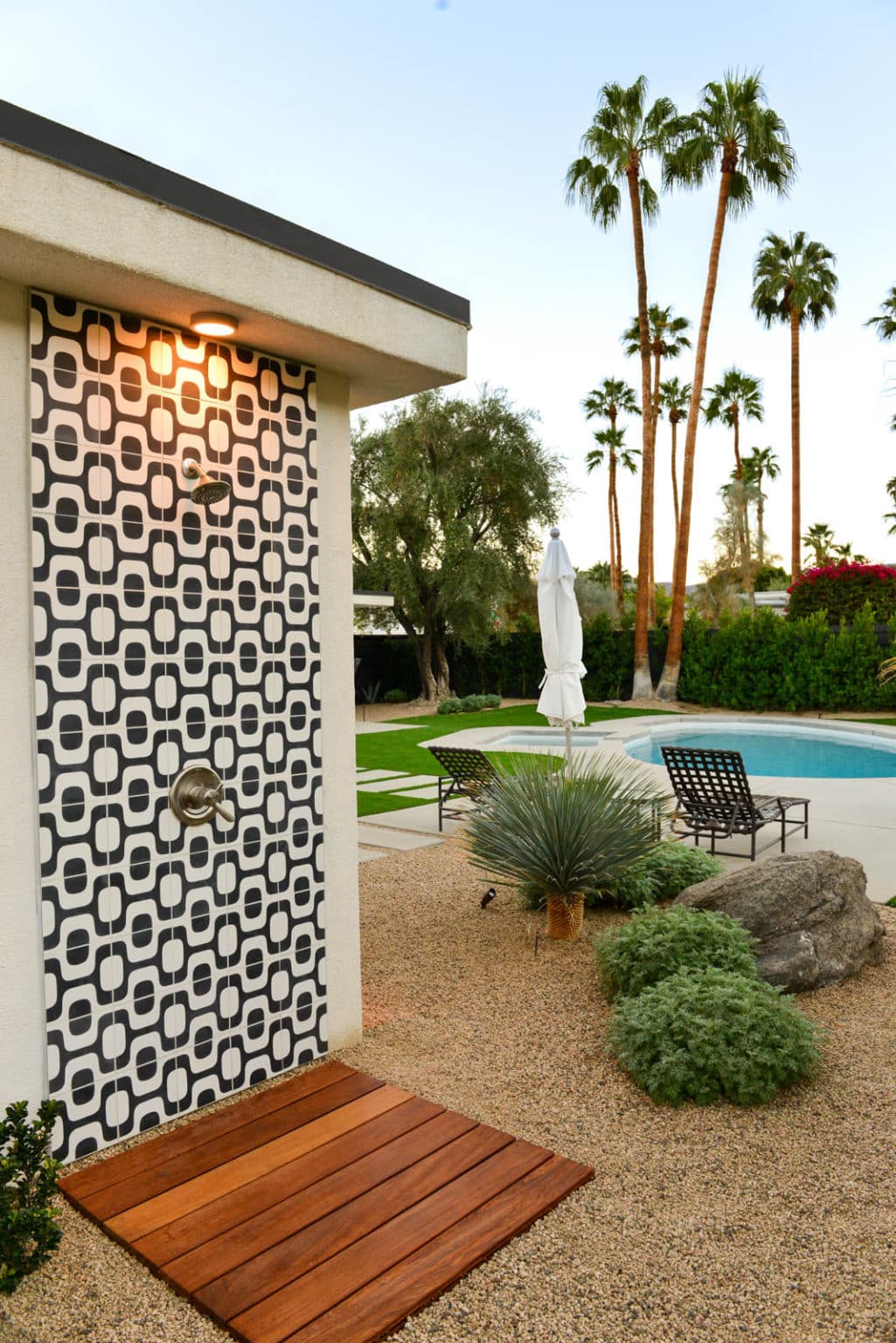 Complete residential landscape design and installation in Palm Springs, including hardscape, custom outdoor shower with tile, fire feature, low voltage lighting, boulders, artificial turf, irrigation and desert plants.