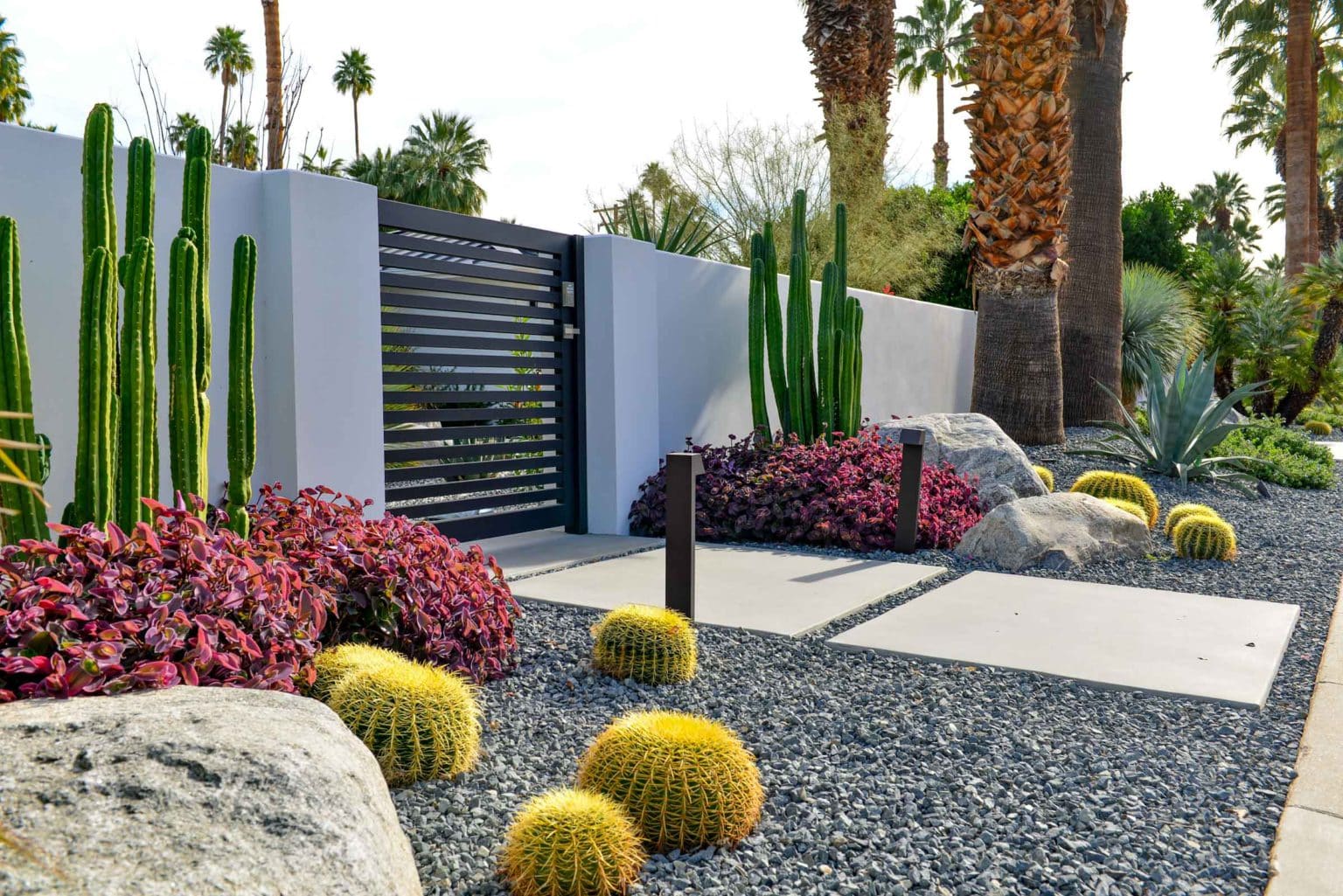 Complete landscape transformation in Palm Springs. Installation includes acid washed hardscape layout, outdoor living area with pizza oven, BBQ, Fireplace, Outdoor shower with breeze block, low voltage lighting, boulders, irrigation and desert plants. Design also includes new driveway automatic gate and new pedestrian entry gate and new garden walls in front yard.