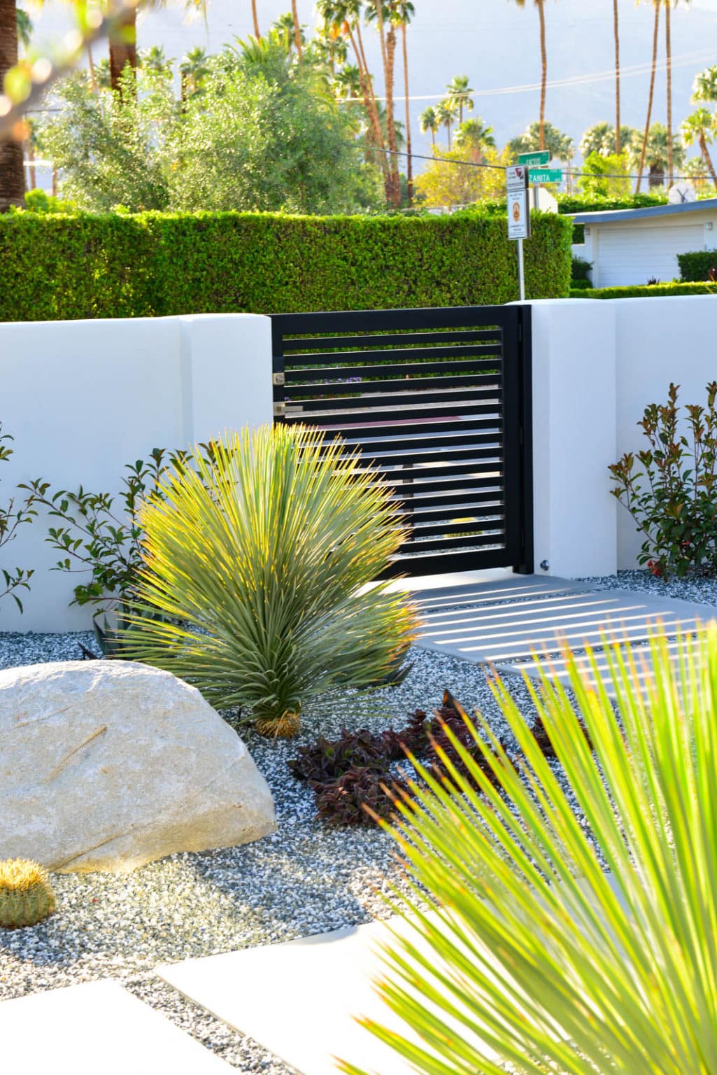 Complete landscape transformation in Palm Springs. Installation includes acid washed hardscape layout, outdoor living area with pizza oven, BBQ, Fireplace, Outdoor shower with breeze block, low voltage lighting, boulders, irrigation and desert plants. Design also includes new driveway automatic gate and new pedestrian entry gate and new garden walls in front yard.