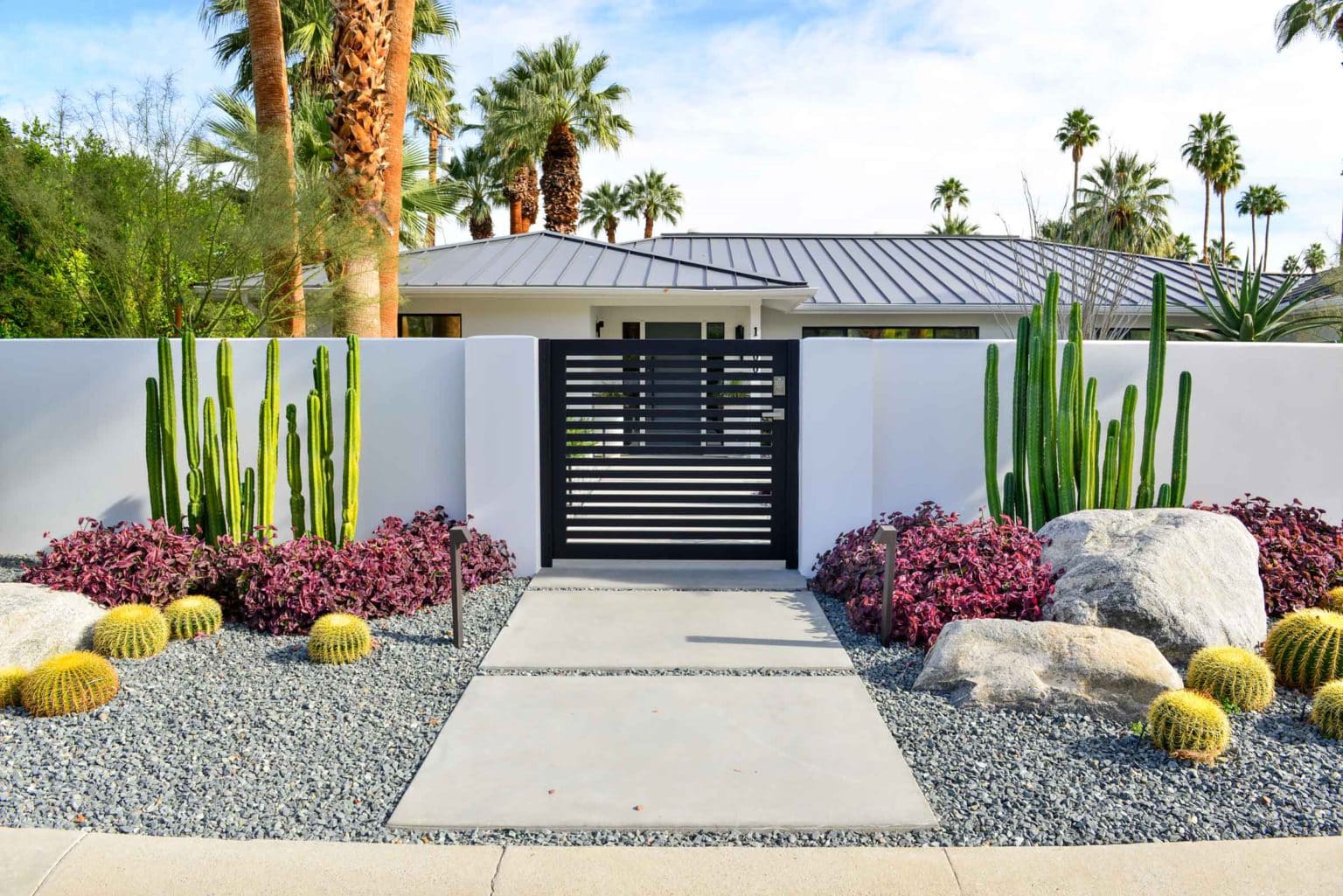 Complete landscape transformation in Palm Springs. Installation includes acid washed hardscape layout, outdoor living area with pizza oven, BBQ, Fireplace, Outdoor shower with breeze block, low voltage lighting, boulders, irrigation and desert plants. Design also includes new driveway automatic gate and new pedestrian entry gate and new garden walls in front yard.