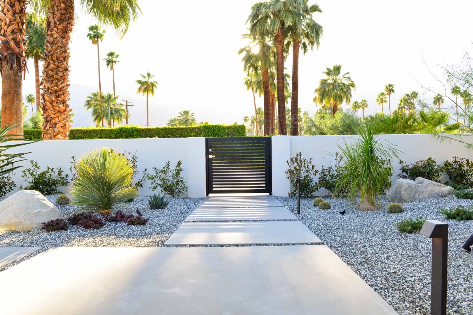 Complete landscape transformation in Palm Springs. Installation includes acid washed hardscape layout, outdoor living area with pizza oven, BBQ, Fireplace, Outdoor shower with breeze block, low voltage lighting, boulders, irrigation and desert plants. Design also includes new driveway automatic gate and new pedestrian entry gate and new garden walls in front yard.