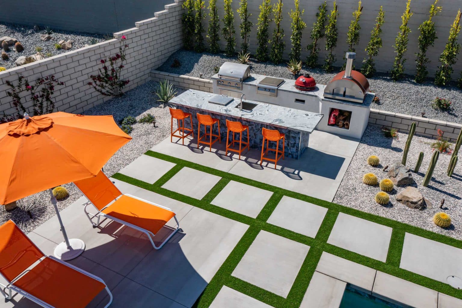 Backyard landscape transformation in Rancho Mirage, including hardscape, outdoor kitchen with pizza oven, low voltage lighting, Boulders, decomposed granite, artificial turf, irrigation and desert plants.