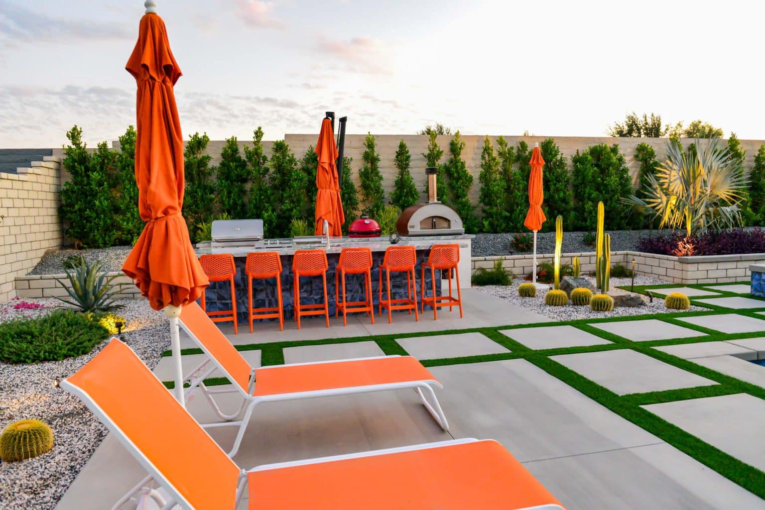 Backyard landscape transformation in Rancho Mirage, including hardscape, outdoor kitchen with pizza oven, low voltage lighting, Boulders, decomposed granite, artificial turf, irrigation and desert plants.