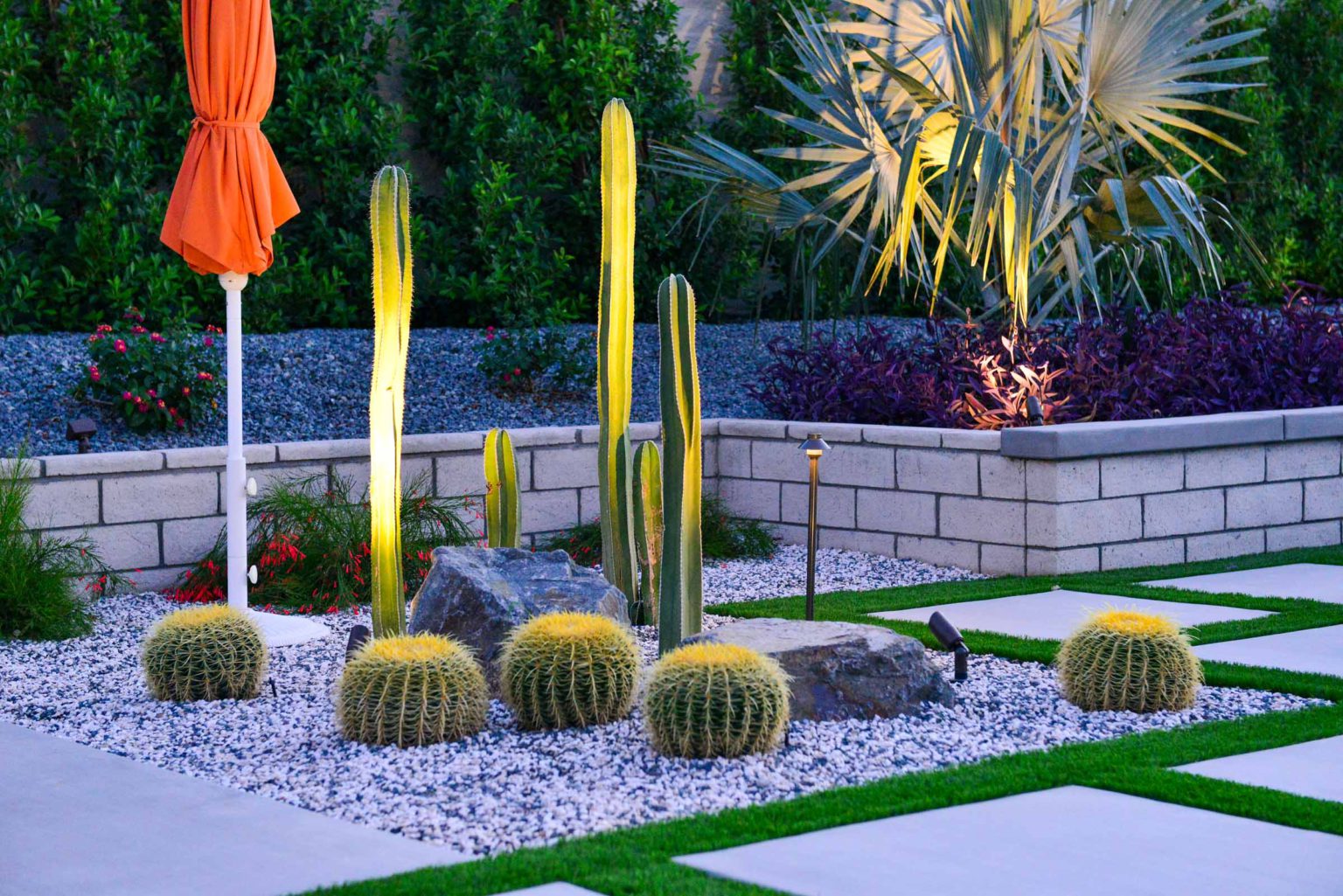 Backyard landscape transformation in Rancho Mirage, including hardscape, outdoor kitchen with pizza oven, low voltage lighting, Boulders, decomposed granite, artificial turf, irrigation and desert plants.