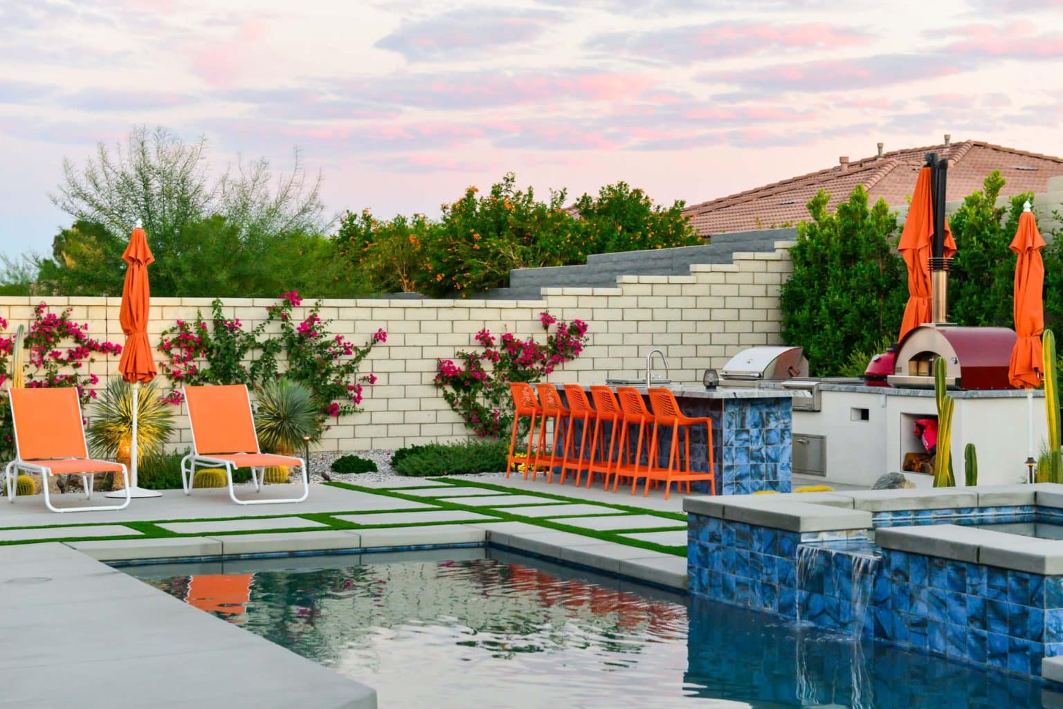 Backyard landscape transformation in Rancho Mirage, including hardscape, outdoor kitchen with pizza oven, low voltage lighting, Boulders, decomposed granite, artificial turf, irrigation and desert plants.