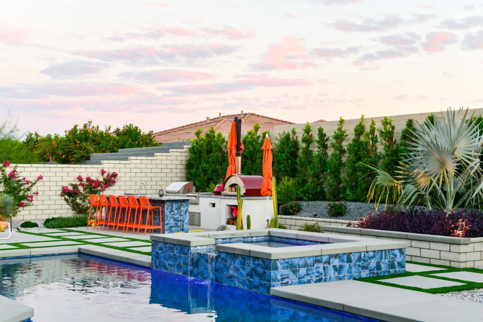 Backyard landscape transformation in Rancho Mirage, including hardscape, outdoor kitchen with pizza oven, low voltage lighting, Boulders, decomposed granite, artificial turf, irrigation and desert plants.