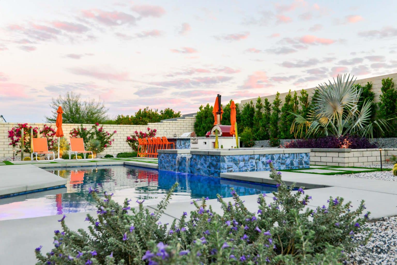 Backyard landscape transformation in Rancho Mirage, including hardscape, outdoor kitchen with pizza oven, low voltage lighting, Boulders, decomposed granite, artificial turf, irrigation and desert plants.