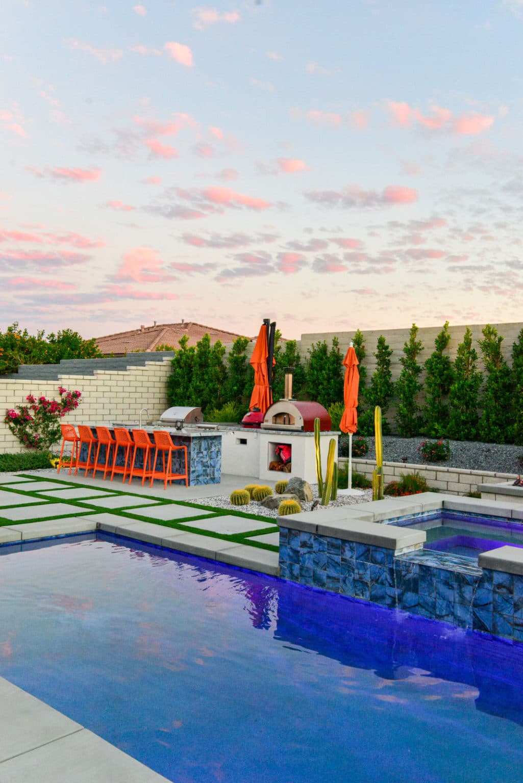 Backyard landscape transformation in Rancho Mirage, including hardscape, outdoor kitchen with pizza oven, low voltage lighting, Boulders, decomposed granite, artificial turf, irrigation and desert plants.