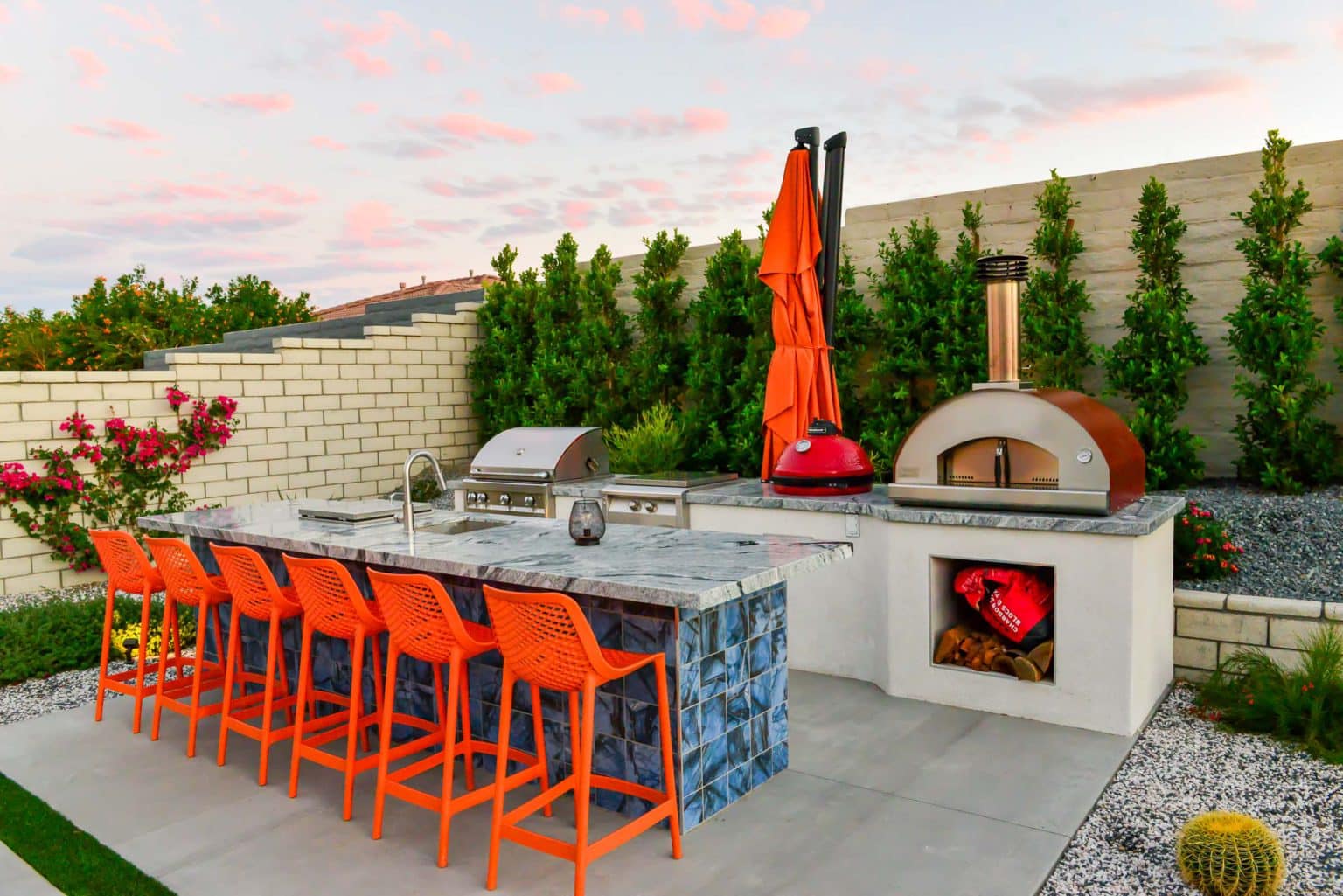 Backyard landscape transformation in Rancho Mirage, including hardscape, outdoor kitchen with pizza oven, low voltage lighting, Boulders, decomposed granite, artificial turf, irrigation and desert plants.