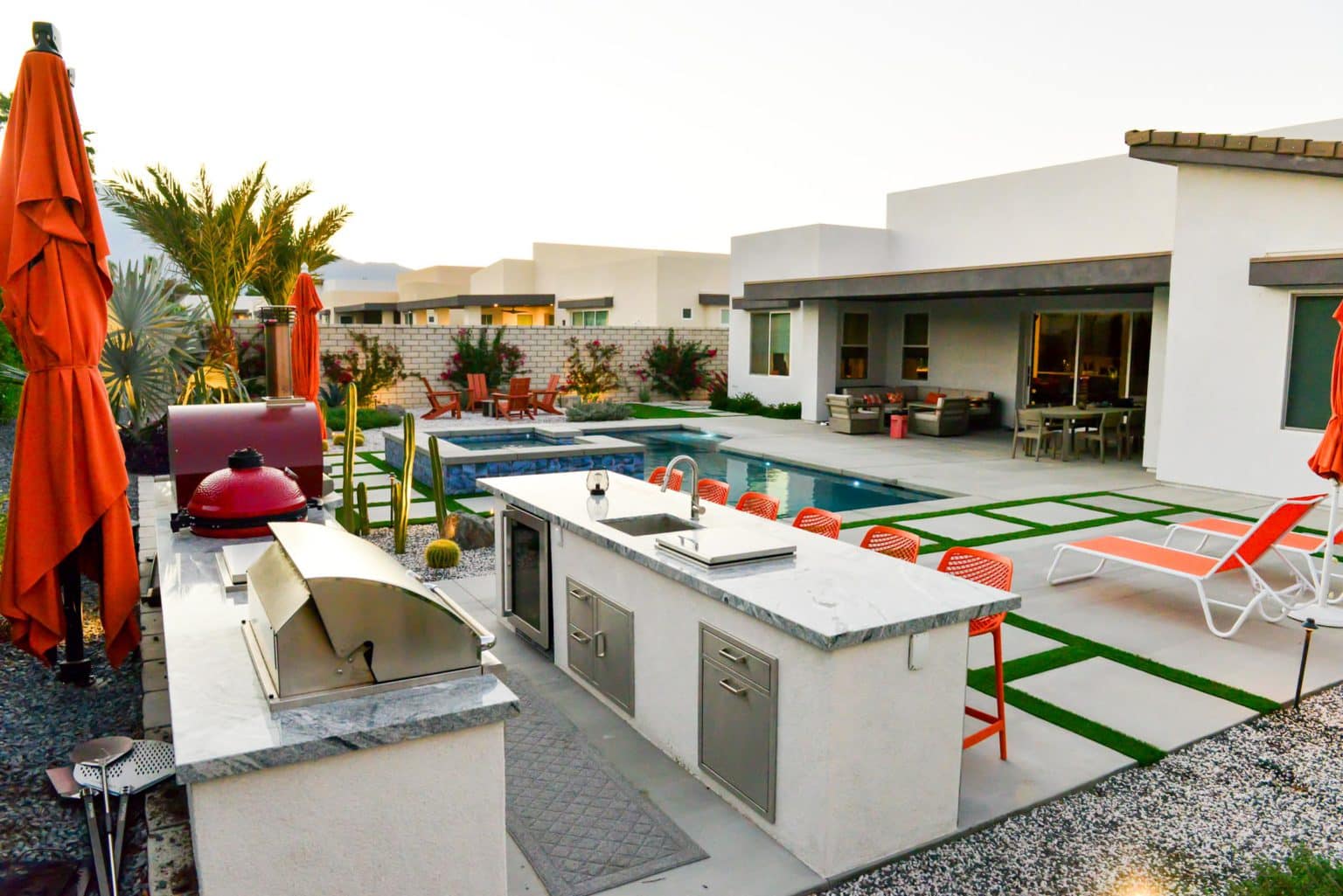 Backyard landscape transformation in Rancho Mirage, including hardscape, outdoor kitchen with pizza oven, low voltage lighting, Boulders, decomposed granite, artificial turf, irrigation and desert plants.