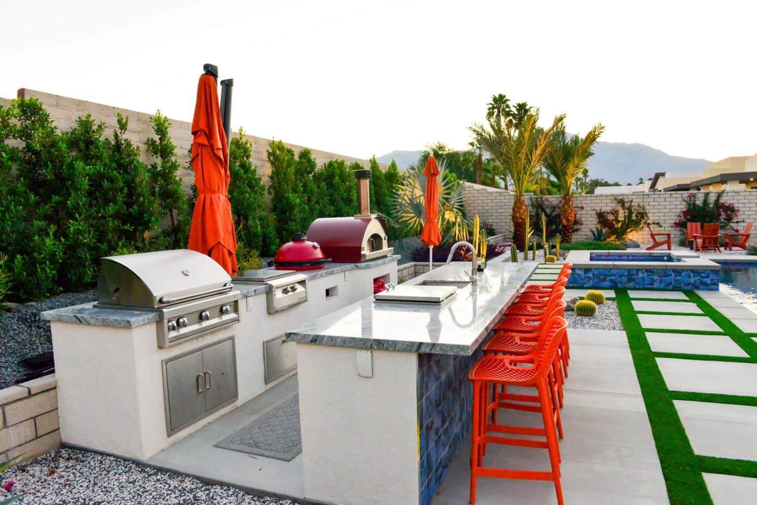 Backyard landscape transformation in Rancho Mirage, including hardscape, outdoor kitchen with pizza oven, low voltage lighting, Boulders, decomposed granite, artificial turf, irrigation and desert plants.