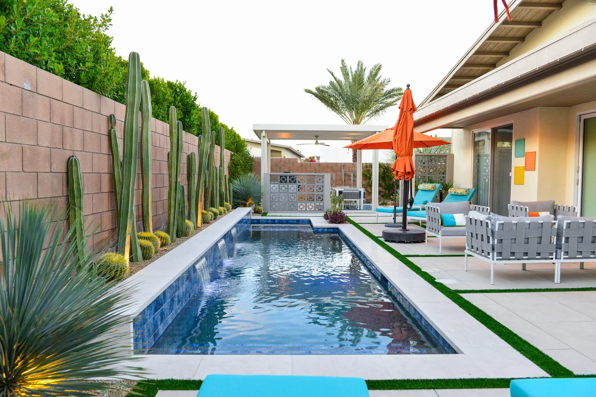 A finished Gus backyard: lap pool, porcelain paver deck with turf joints and columnar cacti along a block wall at the Bliss Way residence
