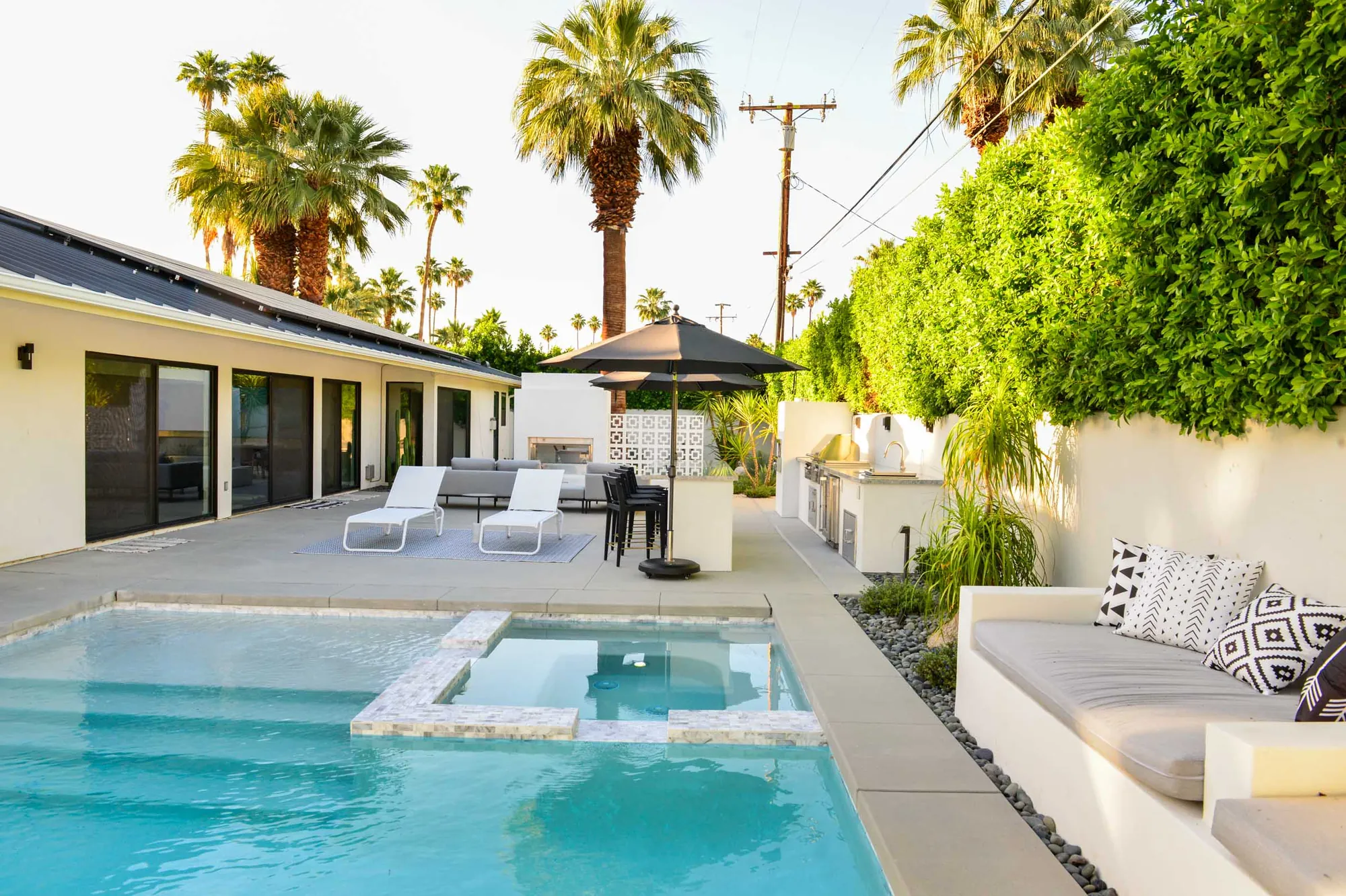 Manzanita backyard after the renovation: pool and raised spa with a white seat wall, palms and a shade umbrella