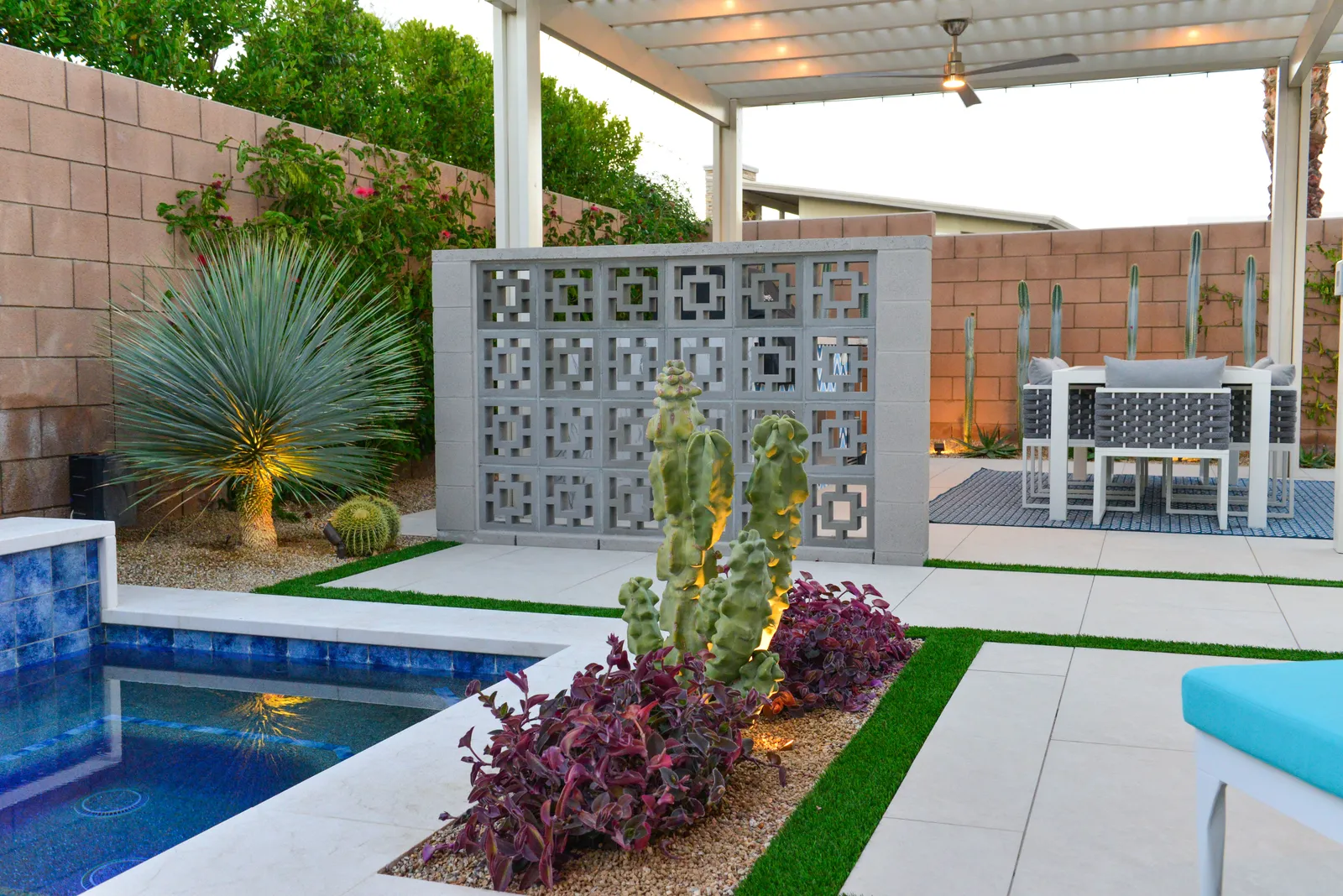 Breeze block privacy screen beside the spa with an uplit totem pole cactus